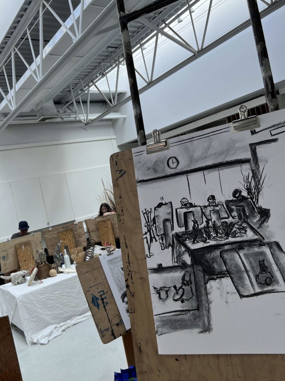 A charcoal drawing of students working on their own art pieces inside one of the art classrooms at VIU.