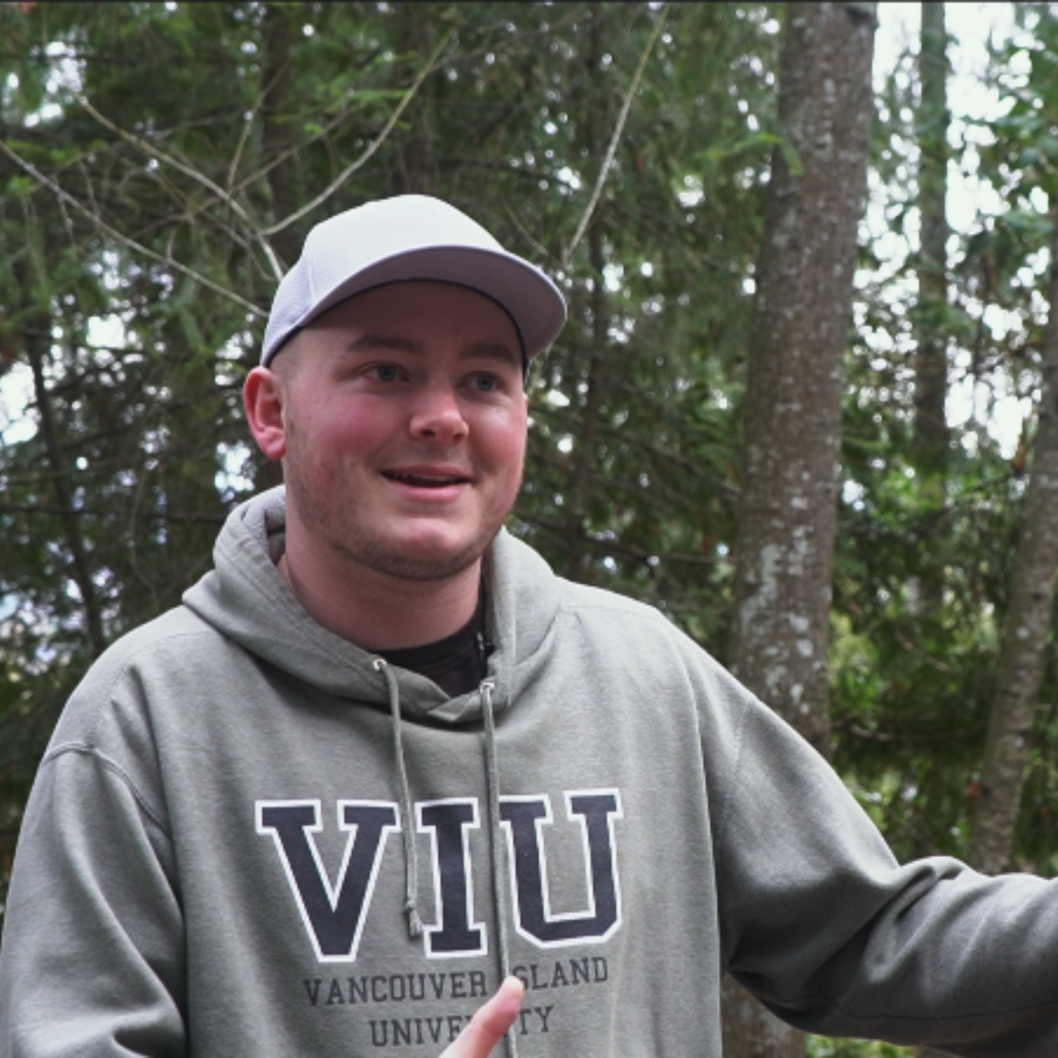 Hunter Jarratt aka @invasivespeciesguy in a VIU hoodie with forest backdrop